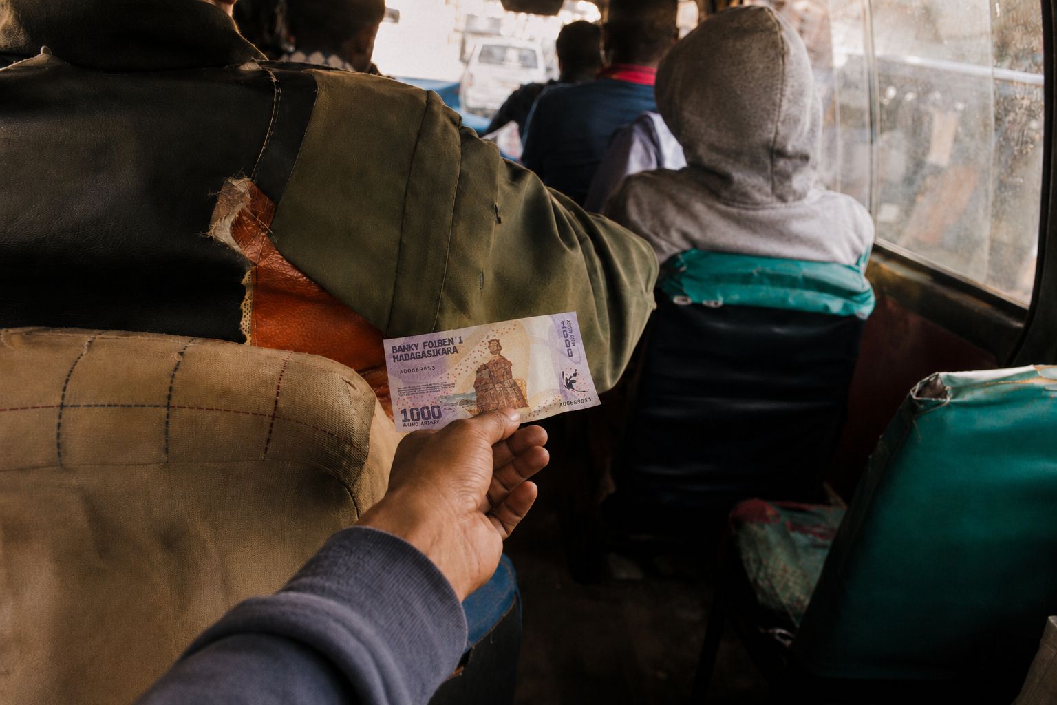 A bord d un taxi-be, une main tend des pieces de monnaie vers l avant